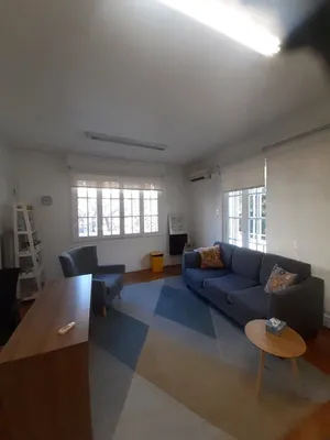 Un box de atención amplio, con un sofá, sillones y dos ventanas que dan al patio.