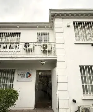 La entrada del centro vista desde el antejardín, con la puerta abierta y el logo en la pared.