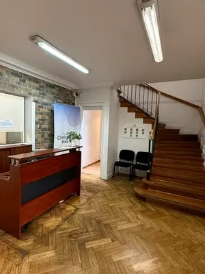 La recepción vista de cuerpo entero, con el mesón, el muro de piedra y la escalera al segundo piso.